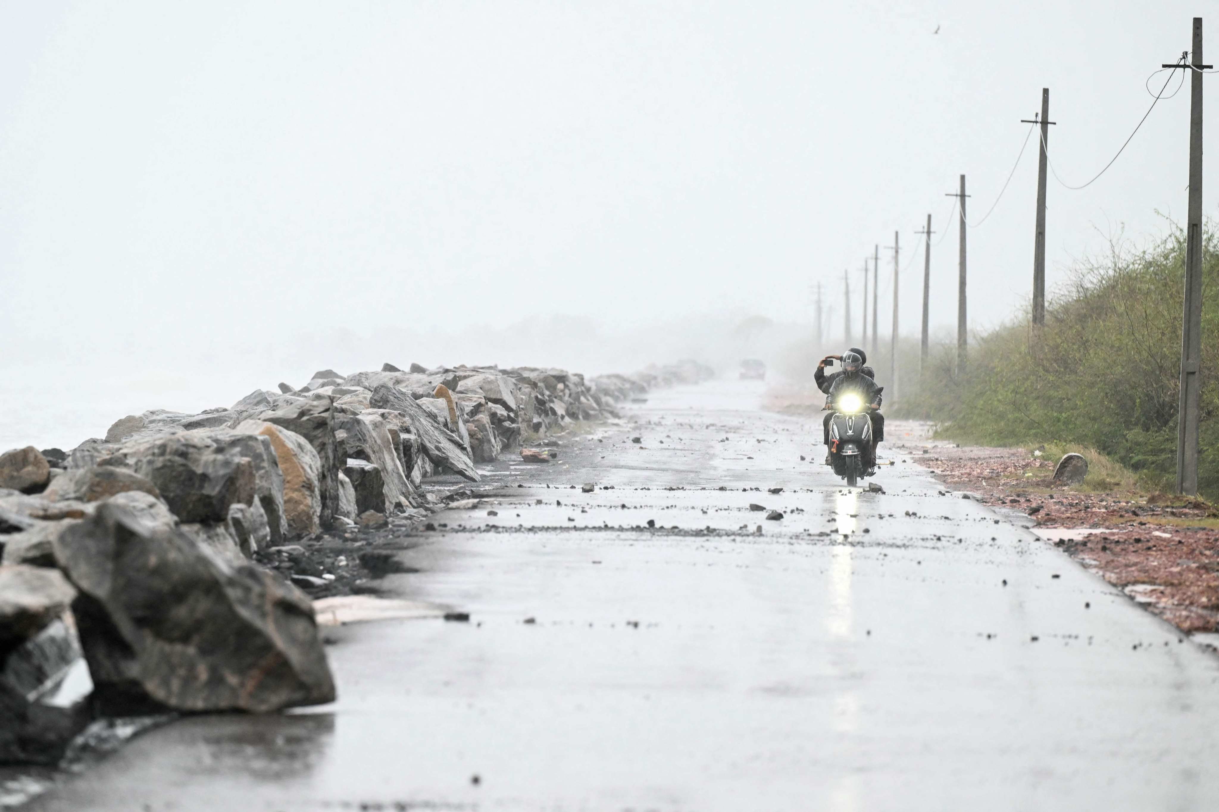 A motorcyclist rides along the Bay of Bengal coast during rainfall in Andhra Pradesh’s Kakinada on Tuesday. Photo: AFP