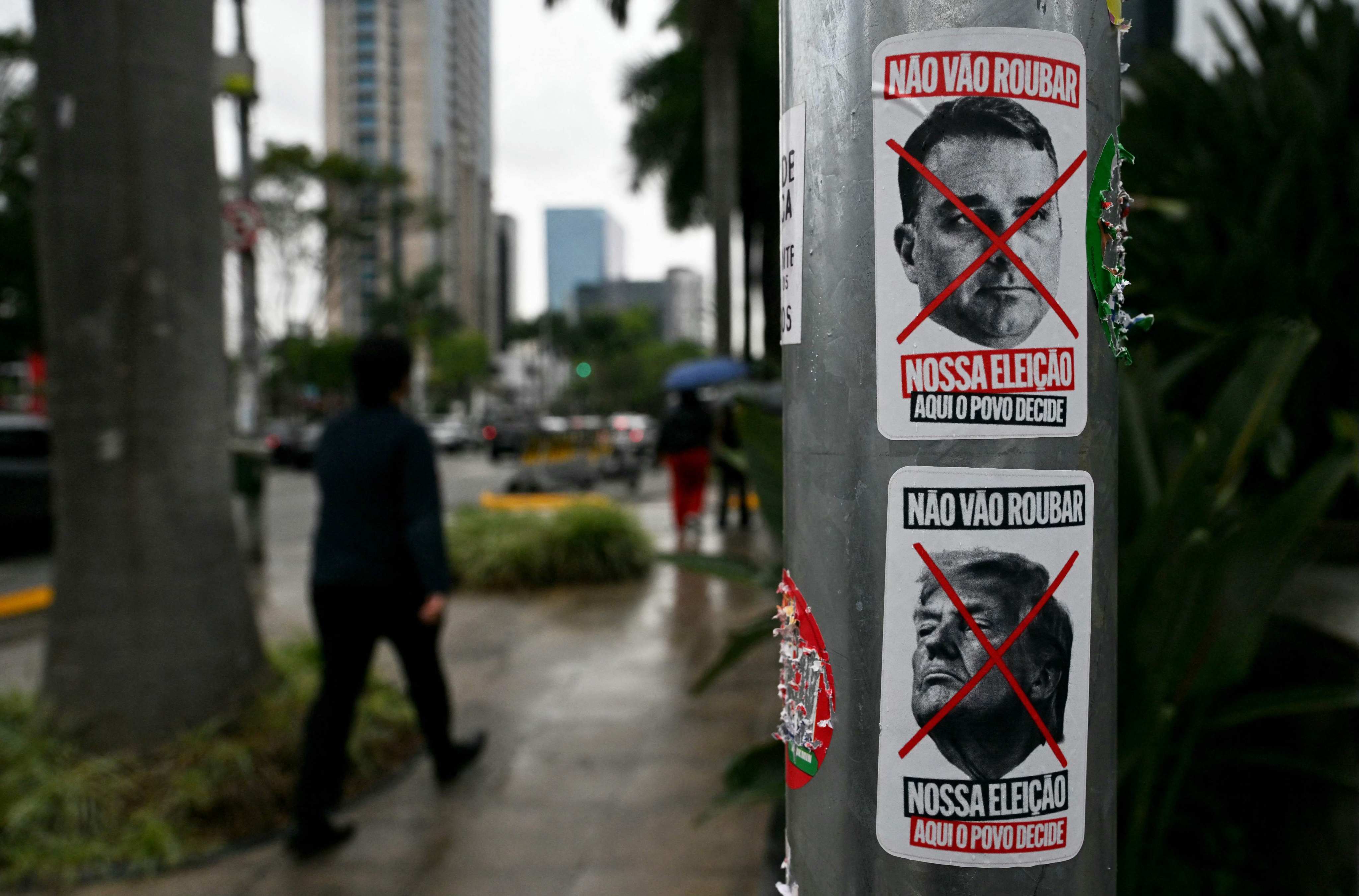 Posters bearing portraits of Flavio Bolsonaro and US President Donald Trump crossed out with a red X on a utility pole in Sao Paulo, Brazil. Photo: AFP