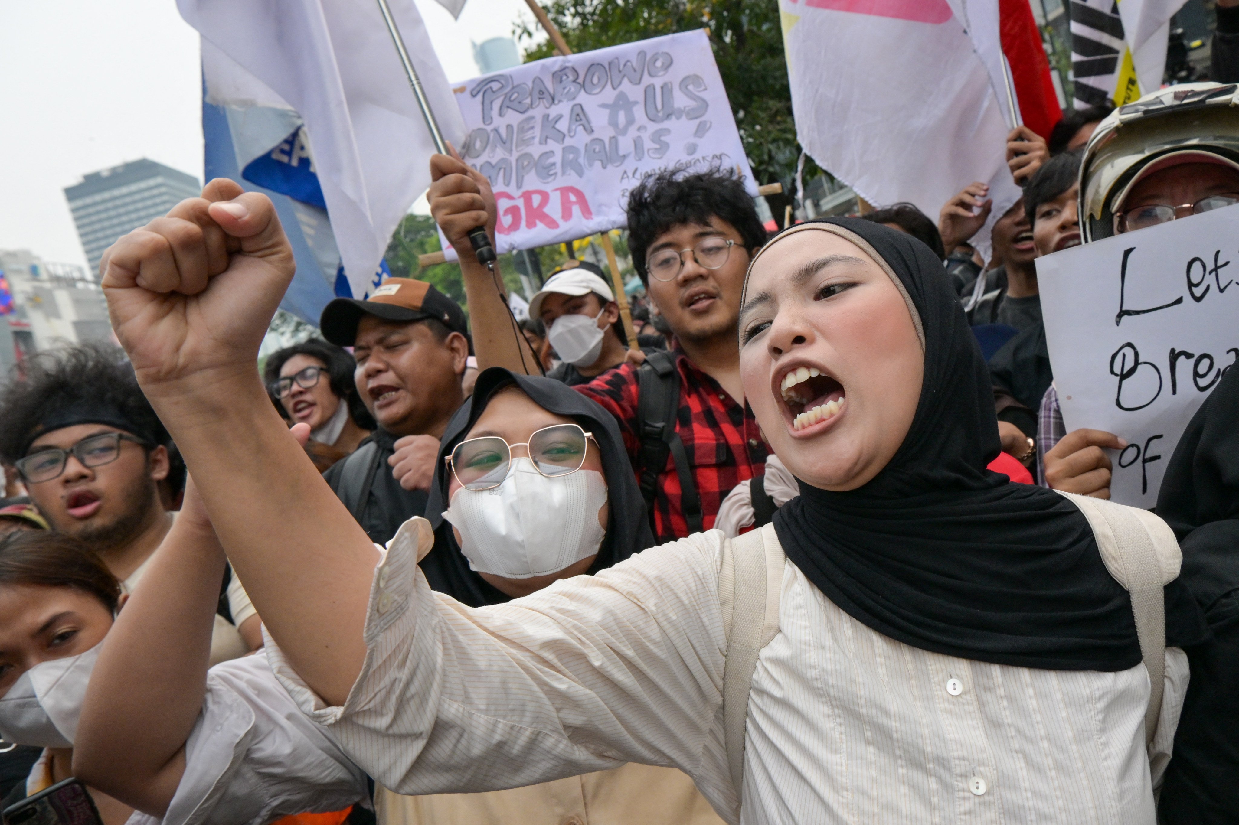 Demonstrators shout slogans and raise their fists alongside signs during a protest against economic hardship, graft and the government’s handling of devastating wildfires causing toxic haze that has sickened thousands in Jakarta on October 28, 2026. (Photo by BAY ISMOYO / AFP)