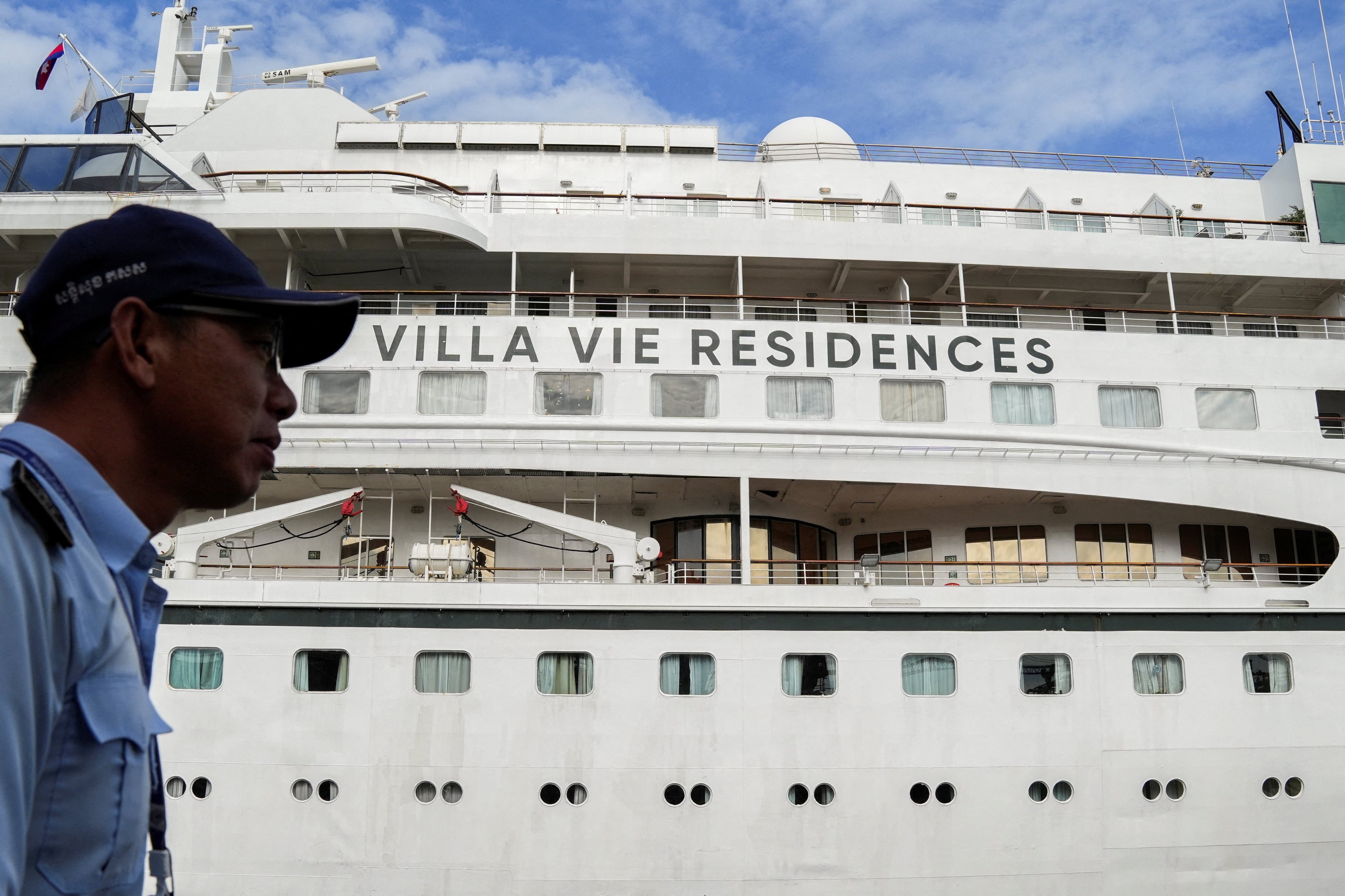 A security staff member stands guard near the Villa Vie Odyssey cruise ship docking at Sihanoukville Autonomous Port, after permanent residents living aboard the vessel were forced to disembark in Cambodia, as the operator said rising fuel prices linked to conflict involving Iran had made operations prohibitively expensive, in Preah Sihanouk province, Cambodia, October 29, 2026. REUTERS/Soveit Yarn