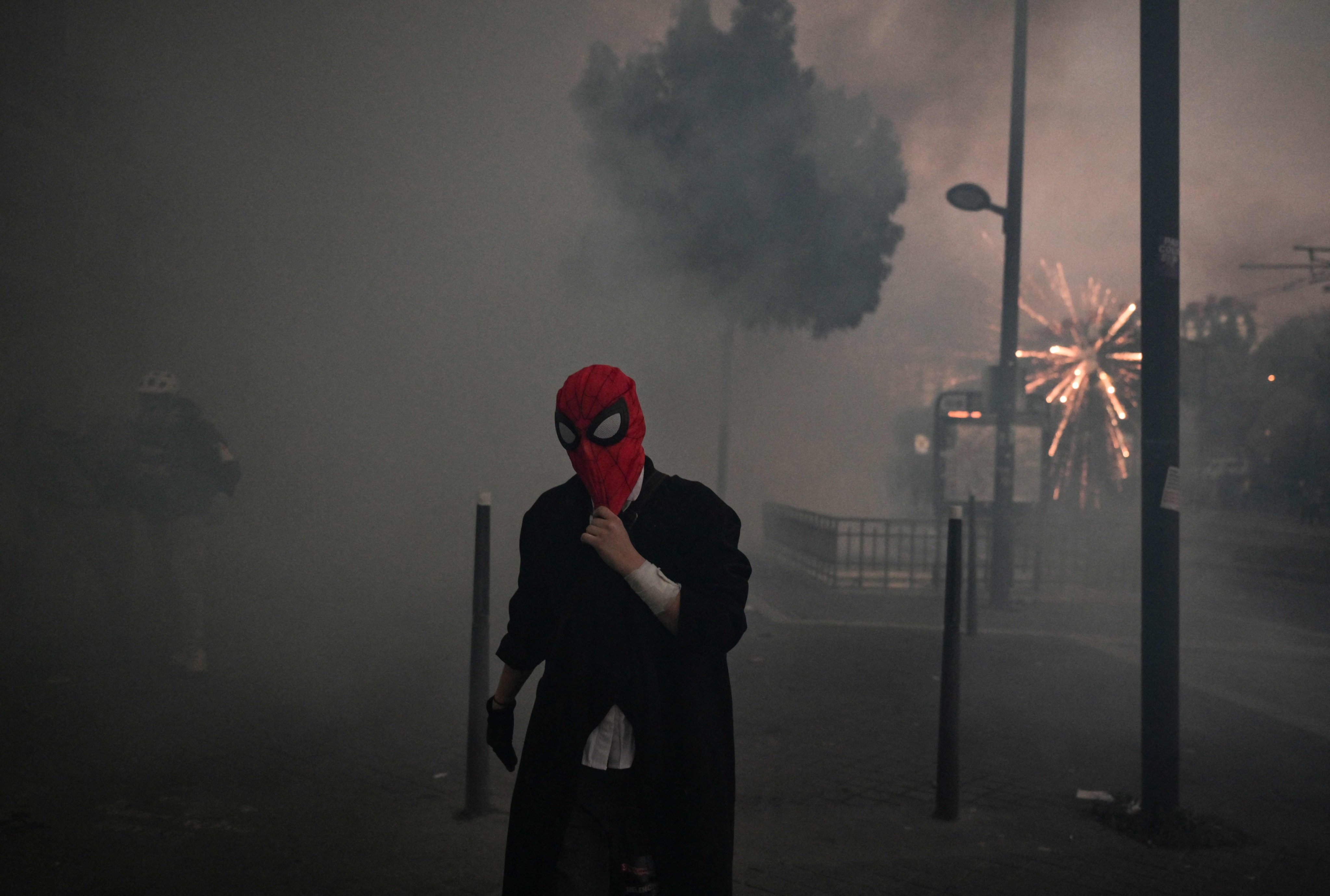 A protester in a Spider-Man mask walks through clouds of tear gas during a demonstration in Paris on Saturday. Photo: AFP