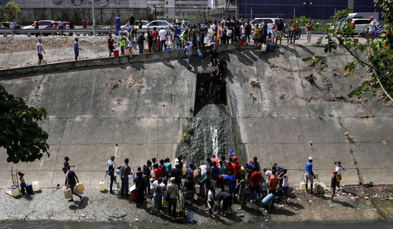 People collect water from a sewage canal in Caracas. Photo: AFP