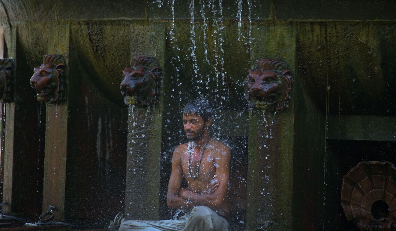 An Indian man cools himself under a public fountain on a hot afternoon in New Delhi. Photo: AP