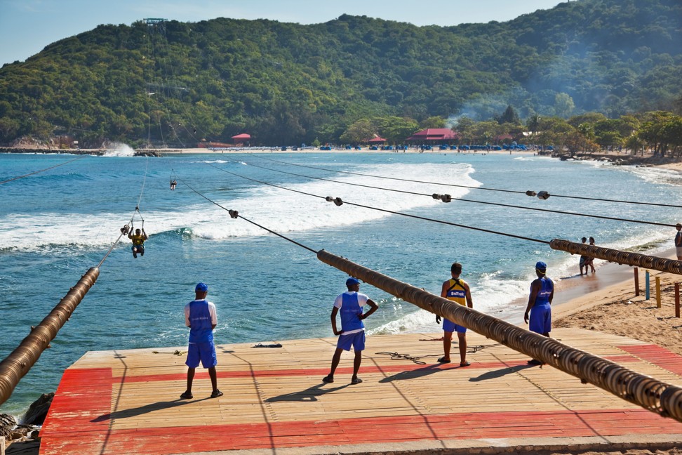 Tourists zip-line in Labadee, Haiti, under the watchful eyes of armed guards, who keep the locals at bay. Photo: Alamy