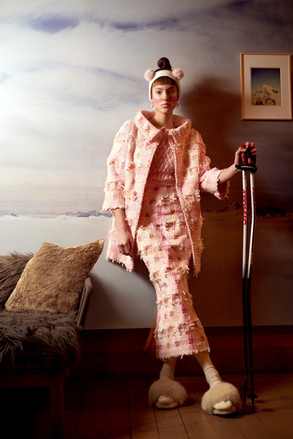 Chanel Haute Couture long coat and dress in pink lace, embroidered with twisted muslin; top of the dress in manually smocked organza, embellished with mother-of-pearl beads; stones and mother-of-pearl earrings and hairpins, embellished with small feathers bouquets by Lemarie and Desrues; Peauluxe slippers; stylist’s own headpiece; Atomic ski poles