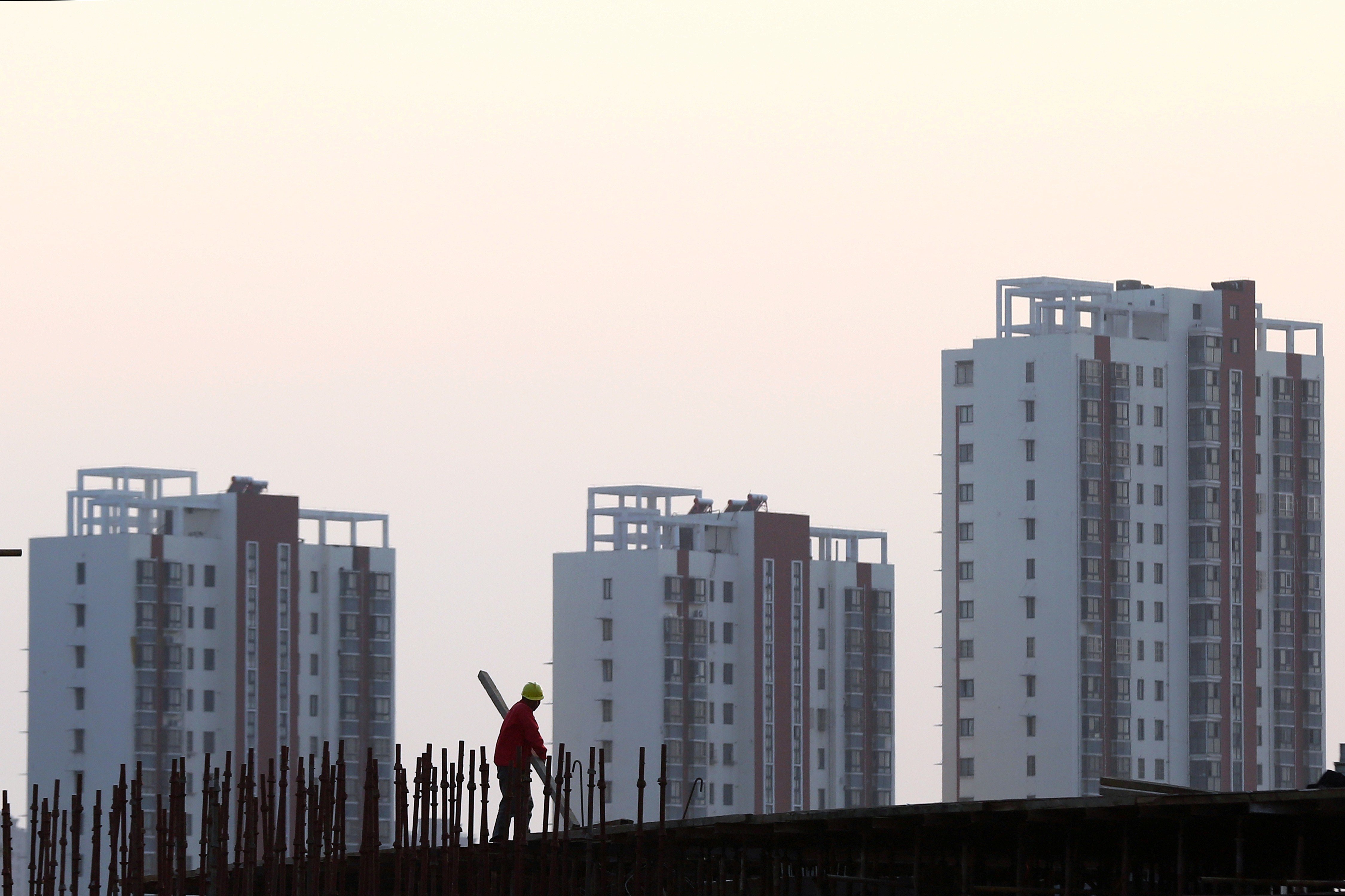 A worker stands on the scaffolding at a construction site against a backdrop of residential buildings in Huaian, Jiangsu province. Photo: Reuters