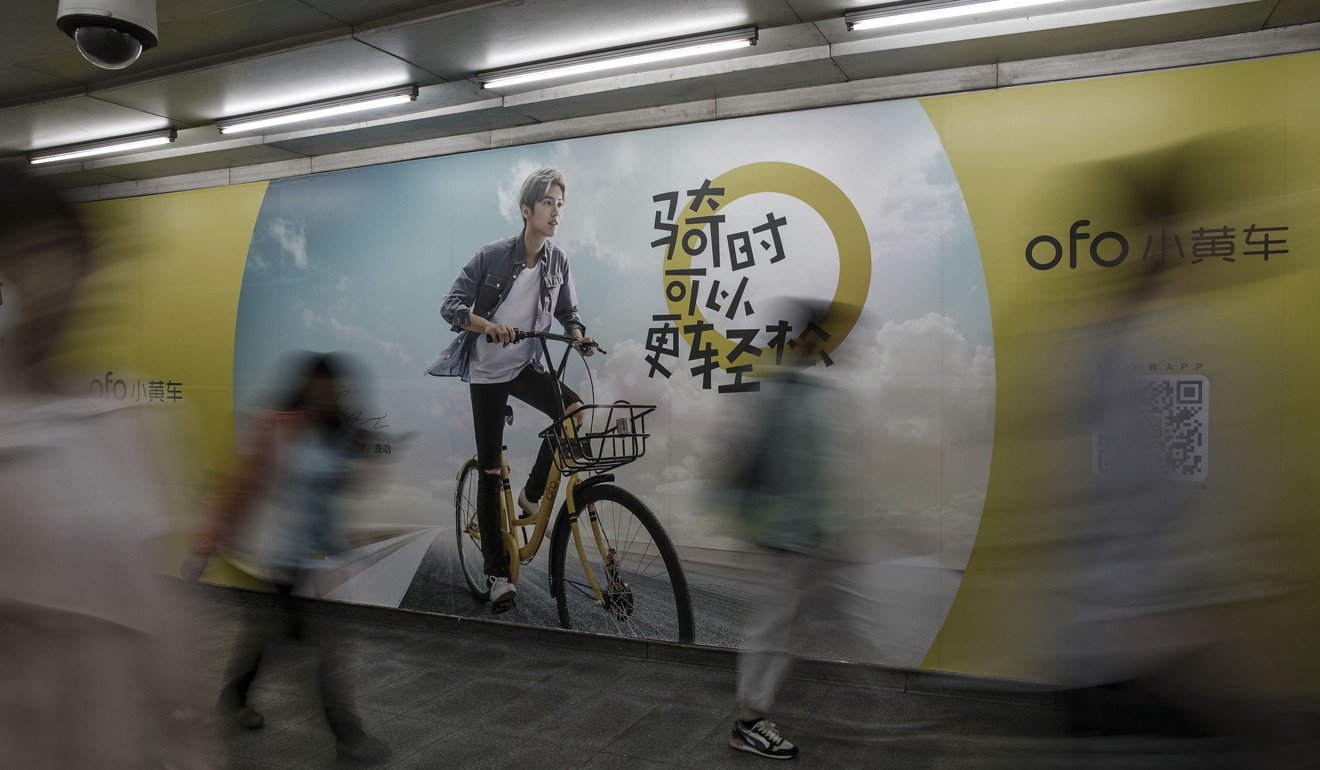 Commuters pass an advertisement for bike-sharing firm Ofo at a subway station in Beijing. Photo: Bloomberg