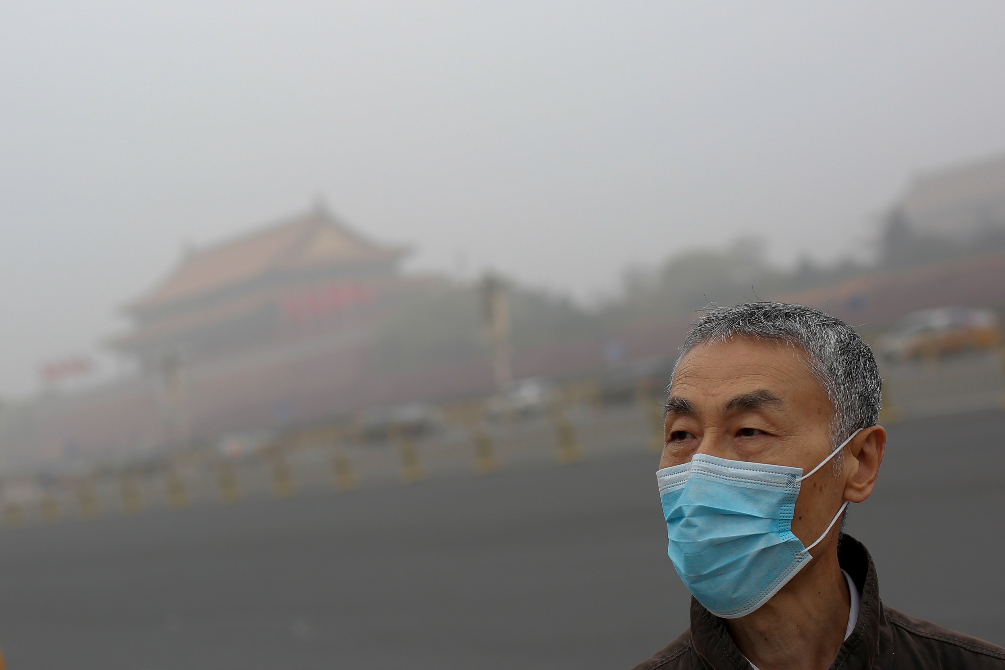 A man wears a mask as Tiananmen Square is shrouded in haze after a yellow alert was issued for smog in Beijing on November 14, 2018. Photo: Reuters