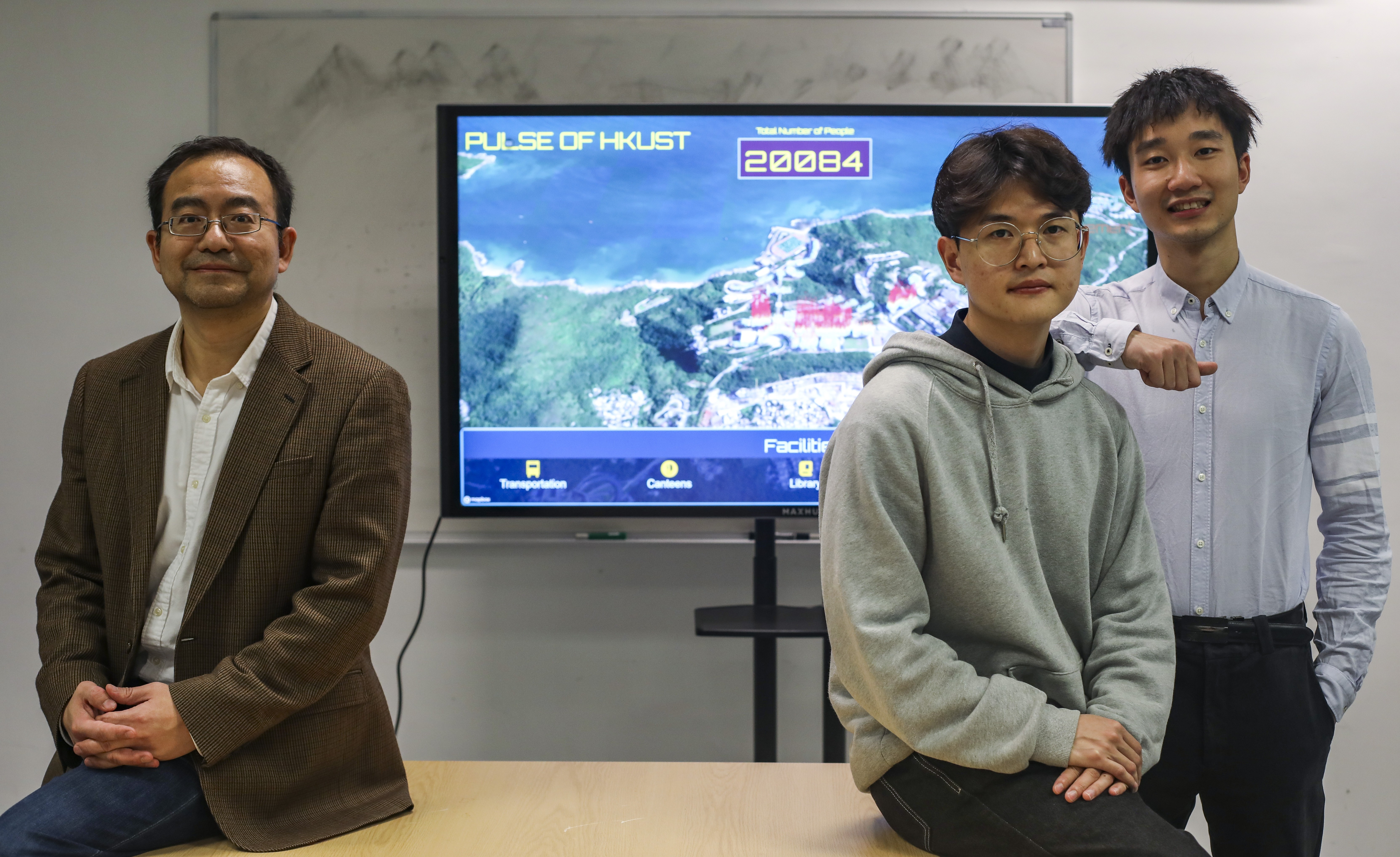 Professor Qu Huamin (left) with his students Steve Ku (centre) and Wu Aoyu. Behind them is the interface of their Pulse app. Photo: Xiaomei Chen