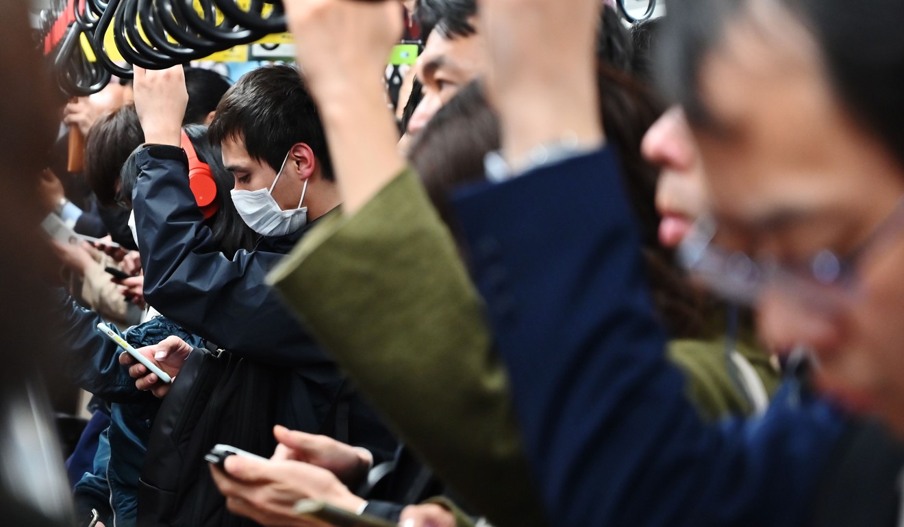 Commuters on their phones while travelling on the Tokyo metro. The Bank of Japan is committed to keeping the yield on 10-year Japanese government bonds around zero, yet Japan’s economy is hardly booming. Photo: AFP