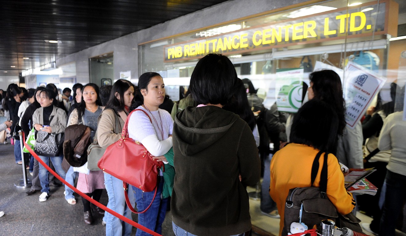 Filipino domestic workers queue up outside a remittance centre in Hong Kong to send money home. Photo: AFP