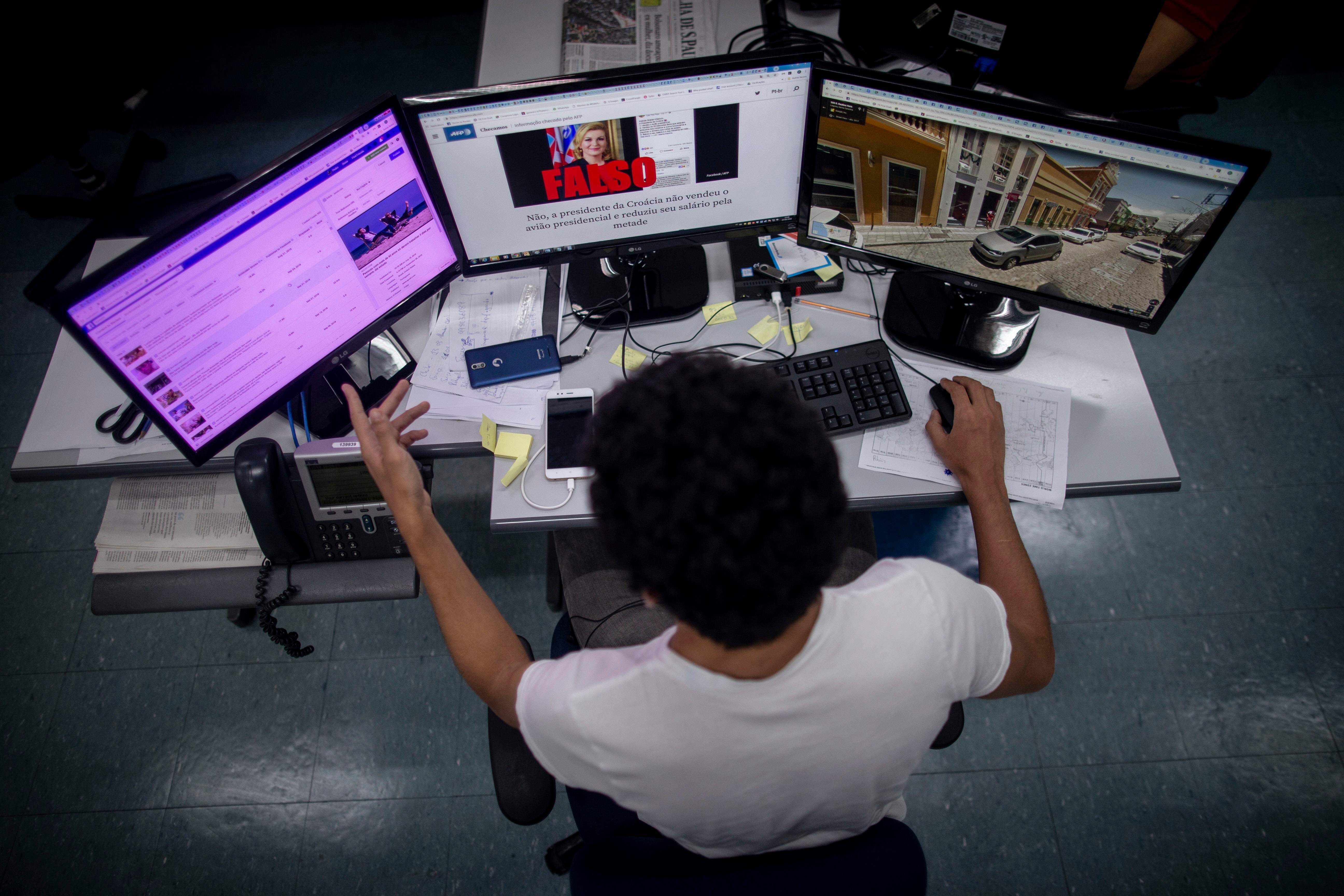 A fact checker navigates multiple screens in the search for fake news. Photo: AFP