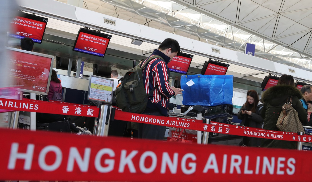 A passenger checks his phone when he waits for luggage registration. Photo: SCMP Pictures
