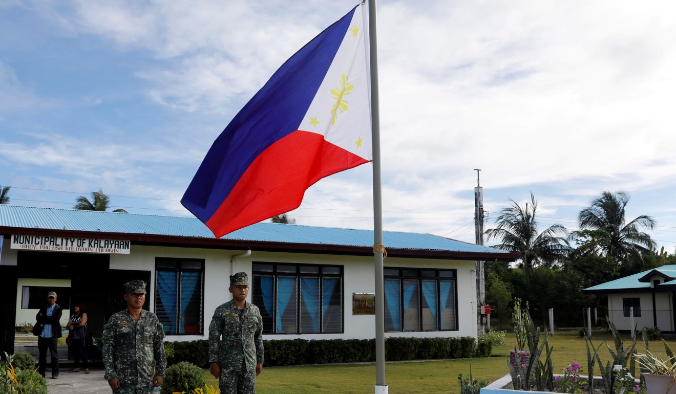 Filipino soldiers stand to attention near a Philippine flag at Thitu Island in the South China Sea on April 21, 2017. The Philippine’s military said it has observed hundreds of Chinese naval vessels circling the island over the past three months. Photo: Reuters
