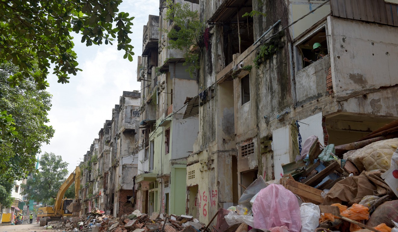 A Cambodian worker (R) looks through a window during demolition work at the White Building residential complex in Phnom Penh. Photo: AFP