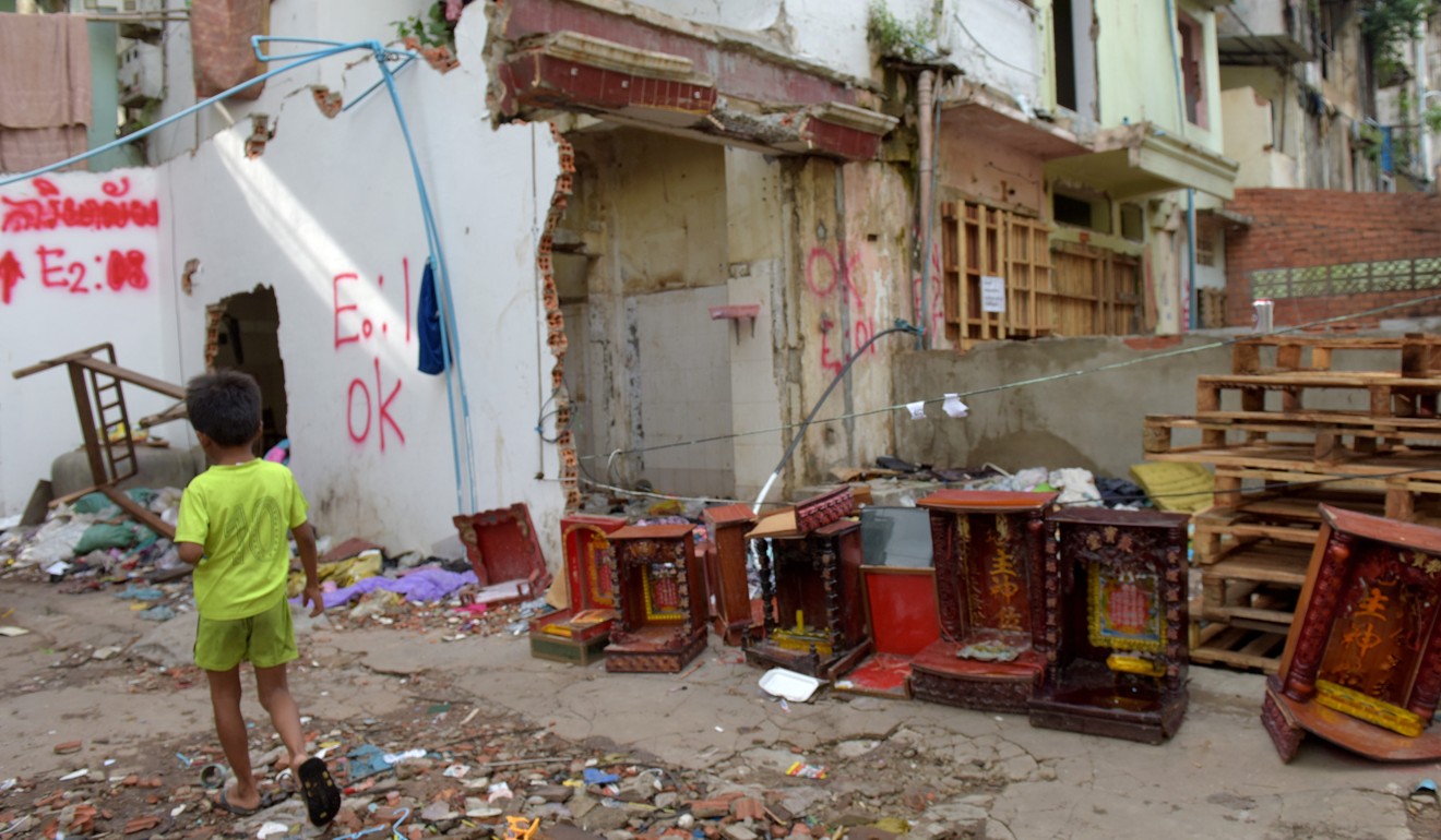 A Cambodian boy walks past spirit houses at the residential complex known as the White Building in Phnom Penh before its demolition. Photo: AFP