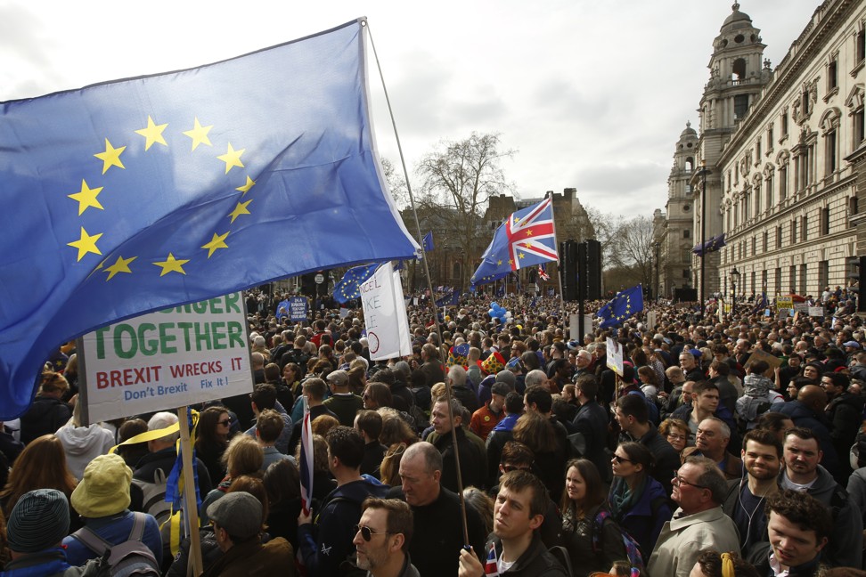 Demonstrators wave a large European Union (EU) flag as they stand on Parliament Square. Brexit is considered a considerable risk to the global economy. Photo: Bloomberg