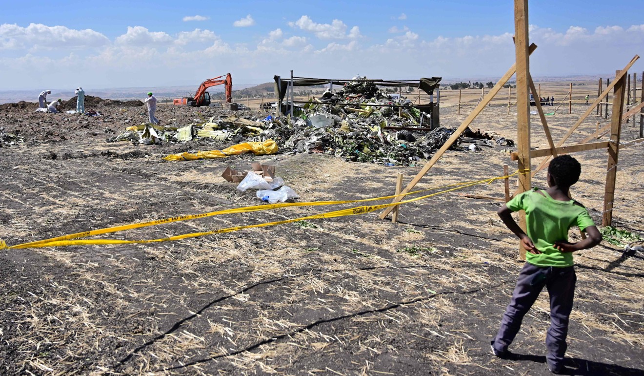 A March 16, 2019 file photo shows a boy watching as forensic investigators comb the ground at the crash site of an Ethiopian Airlines operated Boeing 737 MAX near Bishoftu. Photo: AFP