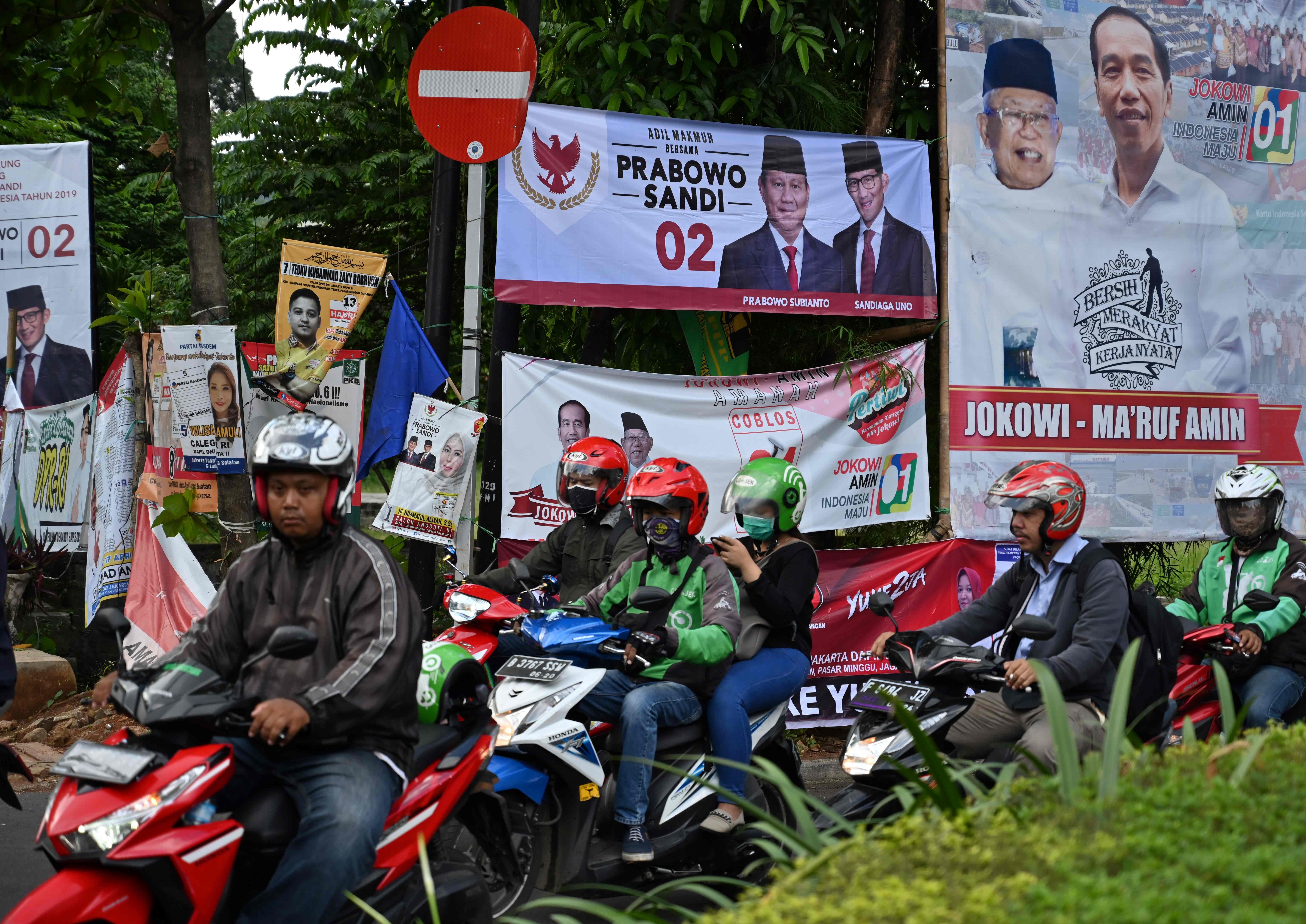 Commuters during rush hour pass banners for various presidential and vice-presidential candidates in Jakarta. Photo: AFP