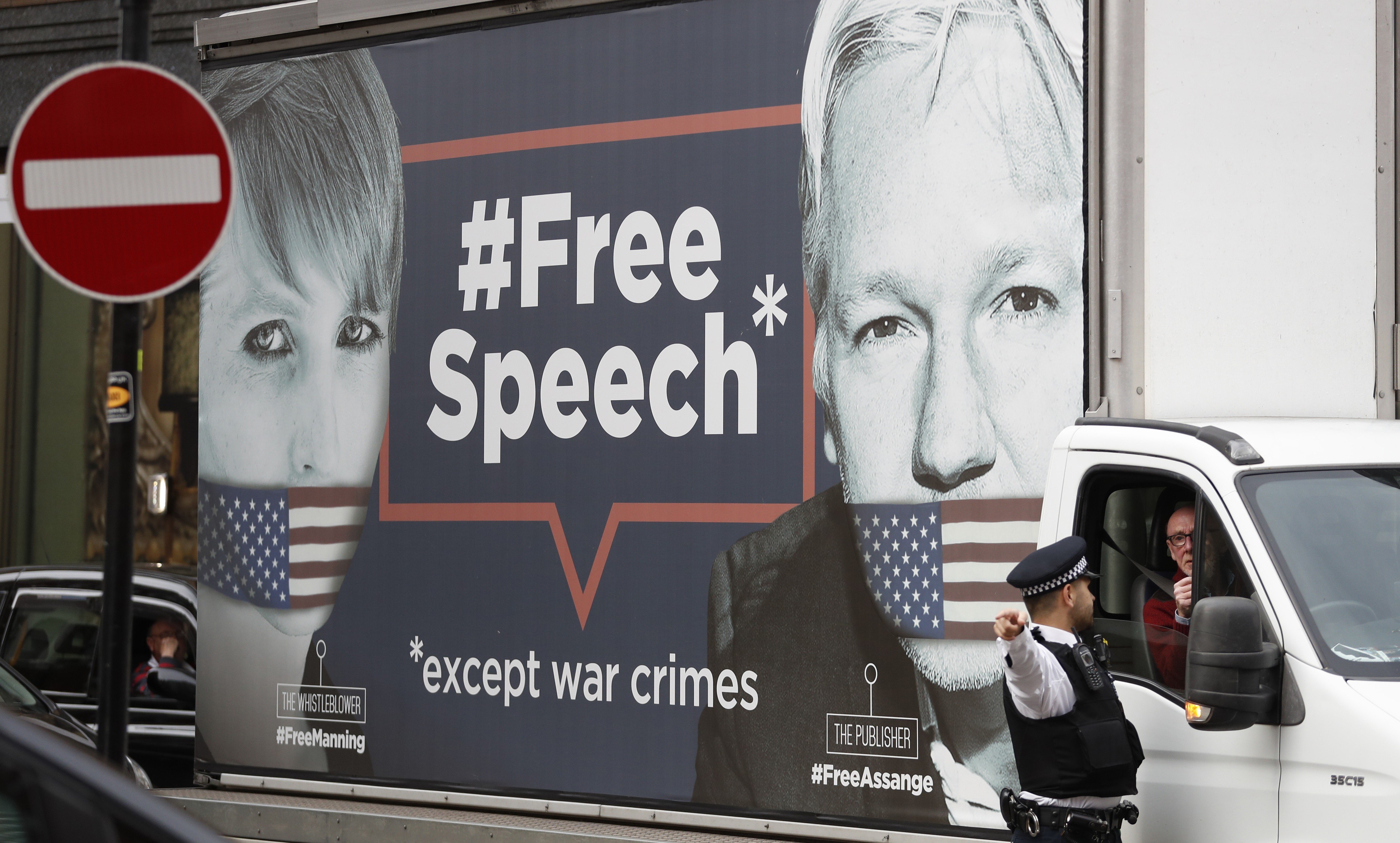 A policeman directs a van with a “Free Speech” placard and the images of Wikileaks founder Julian Assange and whistle-blower Chelsea Manning on its side, near the Ecuadorian Embassy, in London. Photo: AP