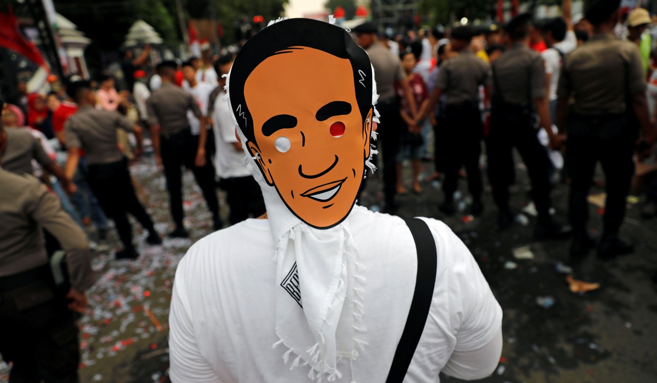 A supporter wears a mask of Indonesian President Joko Widodo. Photo: Reuters