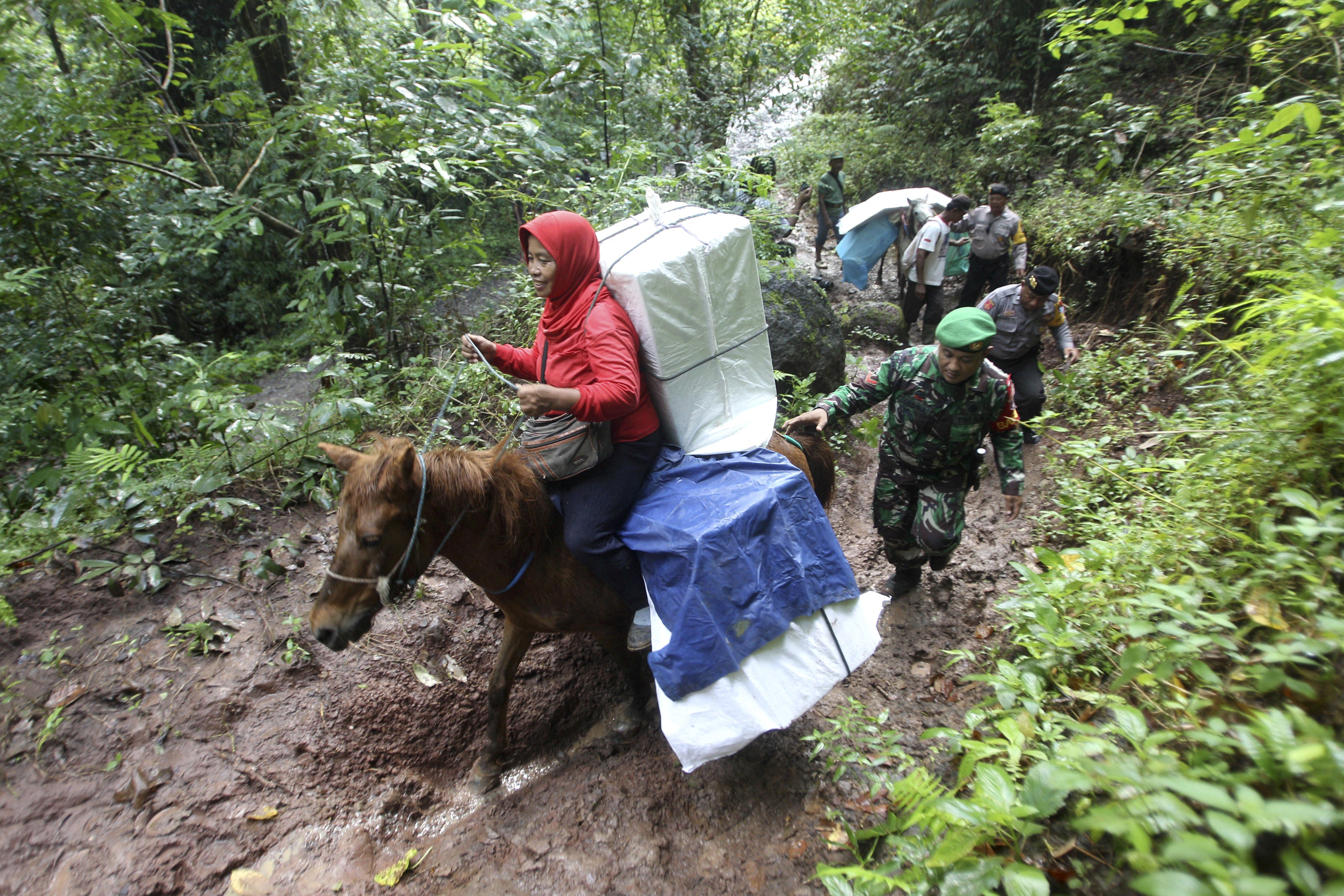 Police officers and soldiers escort electoral workers using horses to distribute ballot boxes and other election paraphernalia to polling stations in remote villages in Tempurejo, East Java. Photo: AP