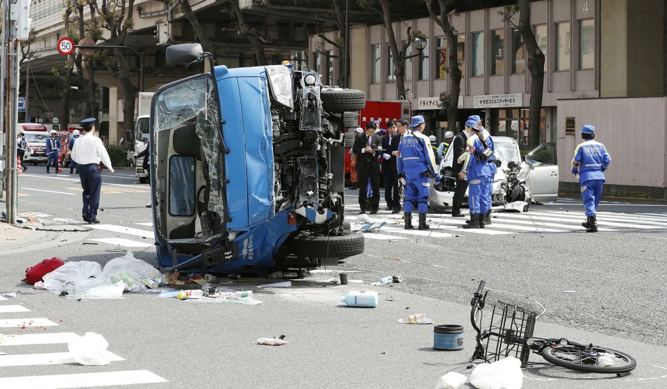 Police inspect the car, right rear, that crashed into a garbage truck, foreground, on a Tokyo street on Friday. Photo: Kyodo