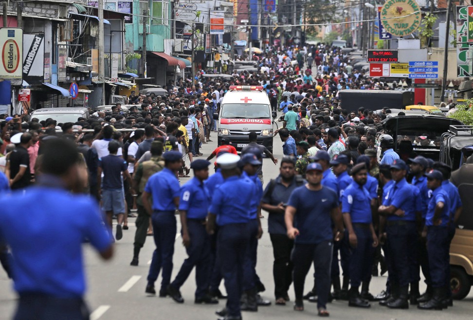Sri Lankan police officers clear the road as an ambulance drives through carrying injured away from one of the attacks in Colombo. Photo: AP