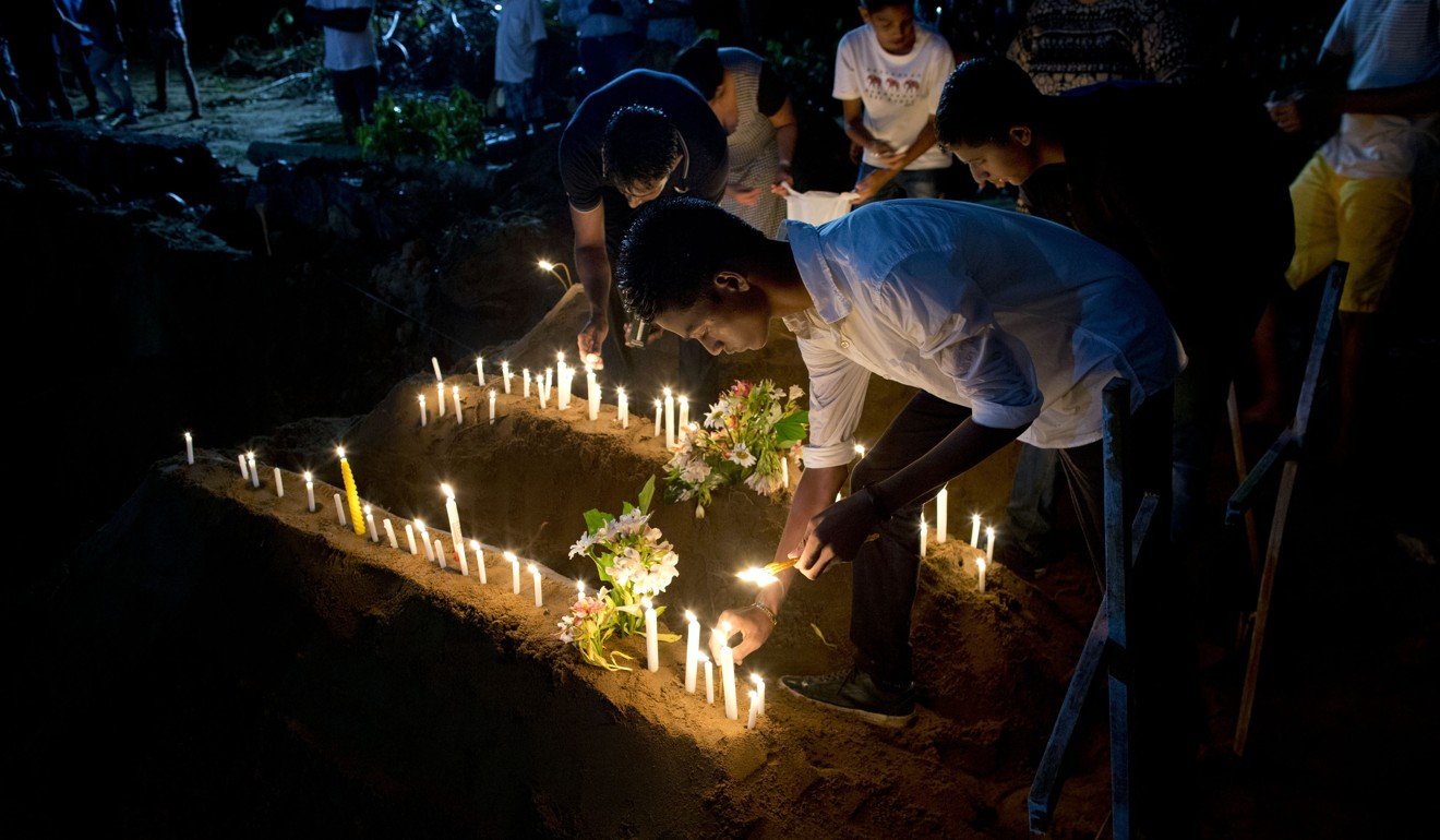 Relatives light candles on Monday after the burial of three victims of the Easter Sunday bomb blasts in Sri Lanka. Photo: AP
