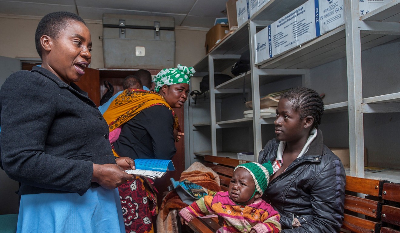 A health surveillance assistant talks to a mother about when she should next bring her child for another dose of the malaria vaccine. Photo: AFP