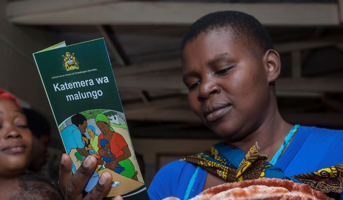 A mother reads a leaflet on malaria at the start of the vaccine implementation pilot project on Tuesday. Photo: AFP