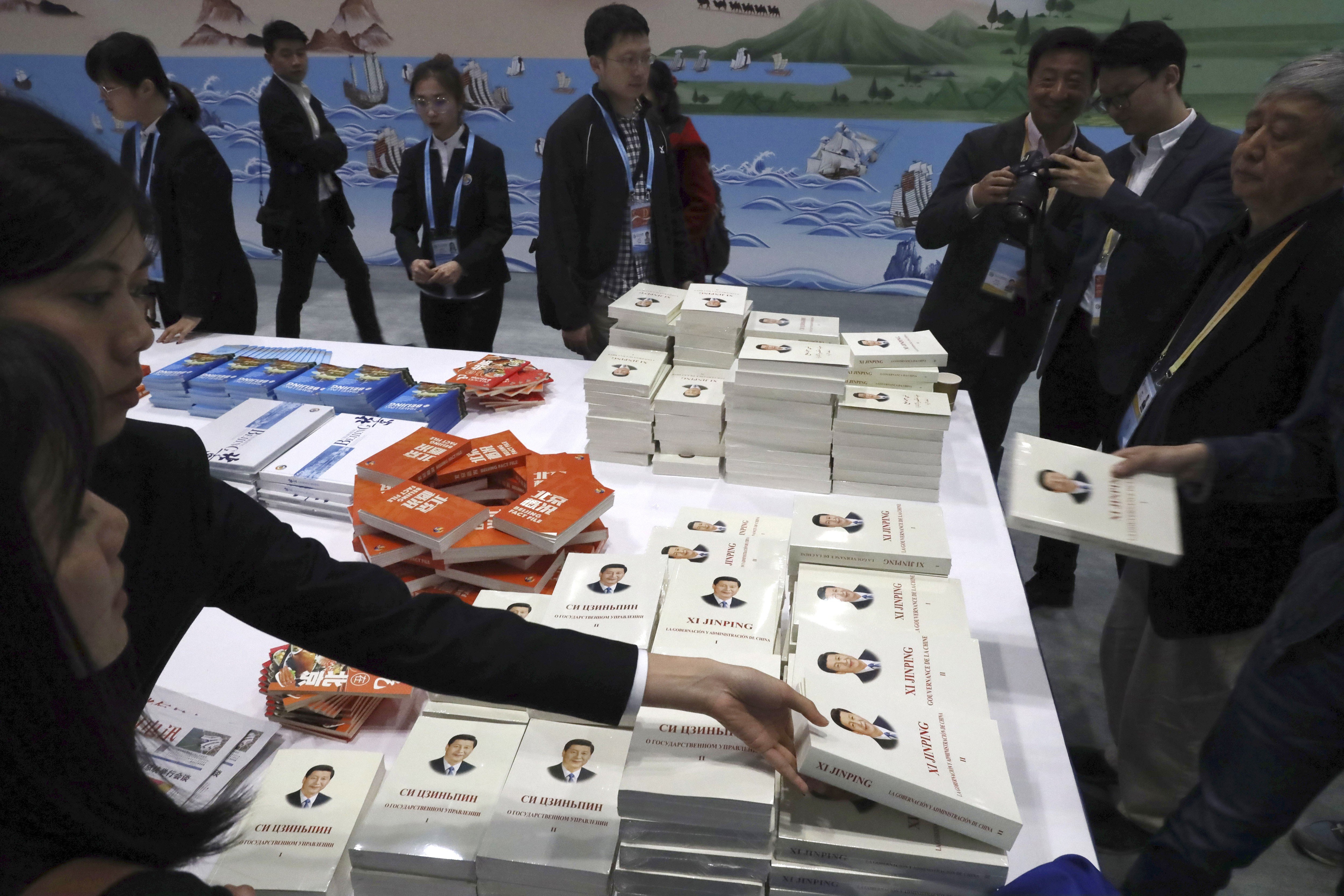 Attendees pick up copies of a book on President Xi Jinping’s governance at the forum’s media centre in Beijing on Friday. Photo: AP