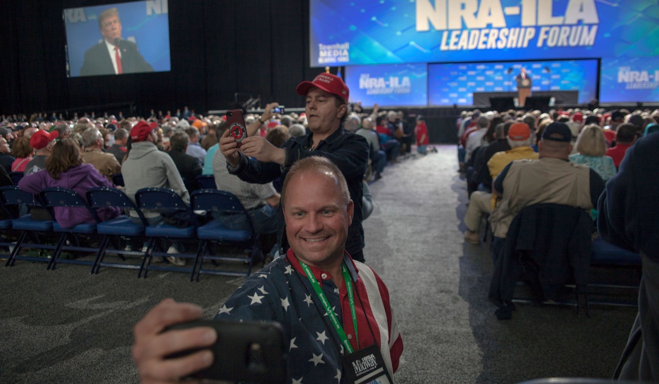 NRA member Skippy Thomas (front) takes a selfie with US President Donald Trump in the background during the NRA’s annual meeting on Friday. Photo: AFP