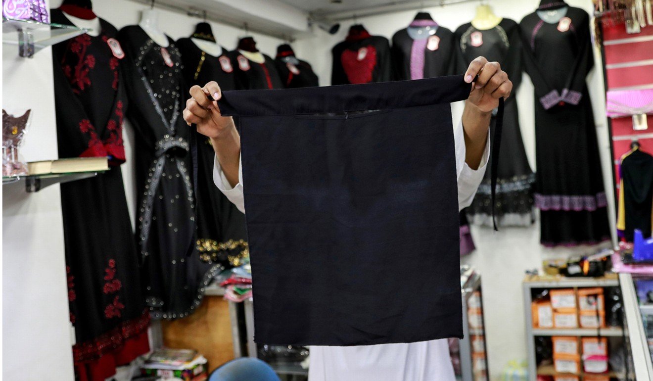 A salesman shows a full face veil, or niqab, at a shop for Muslim women in Colombo. Photo: Reuters