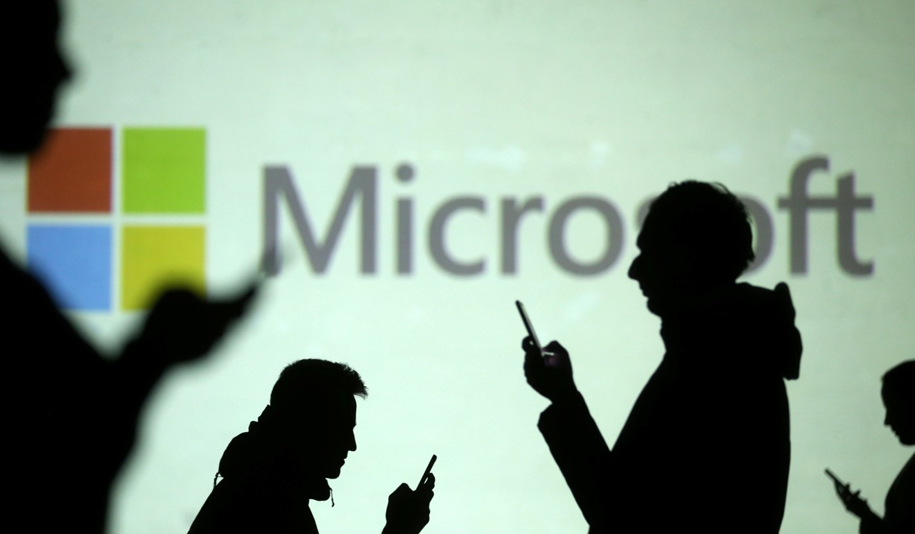 REFILE - CLARIFYING CAPTION Silhouettes of mobile users are seen next to a screen projection of Microsoft logo in this picture illustration taken March 28, 2018. REUTERS/Dado Ruvic/Illustration