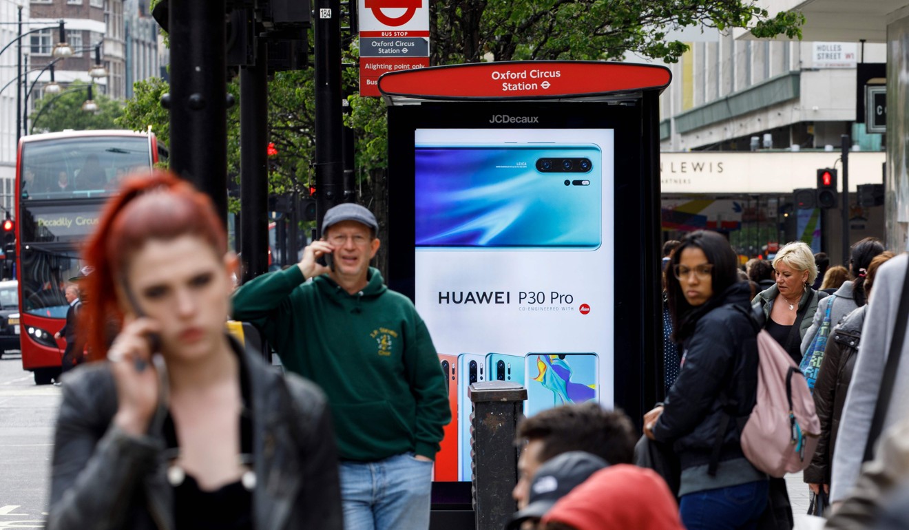 Pedestrians use their mobile phones near a Huawei advert at a bus stop in central London on Monday. Photo: AFP
