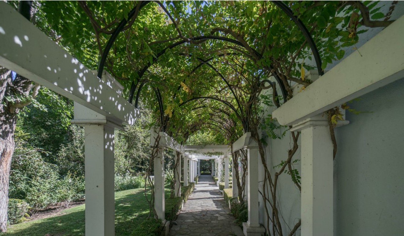 An arched walkway leads through a manicured lawn. Photo: Keller Williams/Beverly Hills