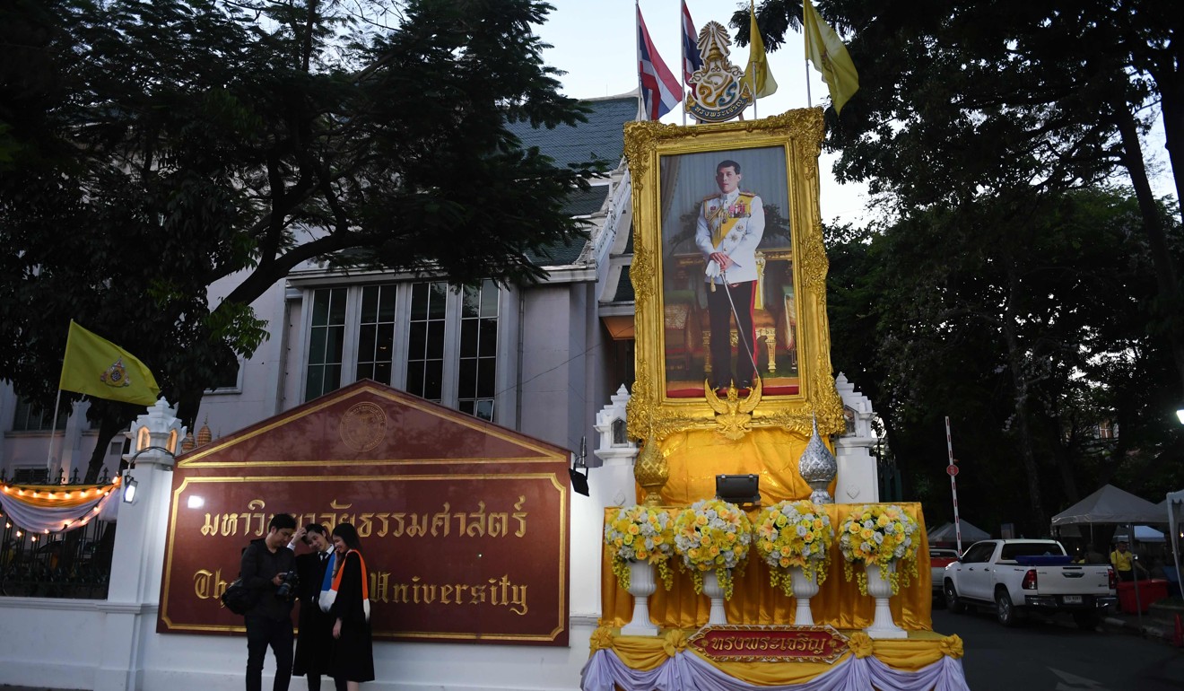 Thammasat University students take graduation photos beside a portrait of Thailand's king. Photo: AFP