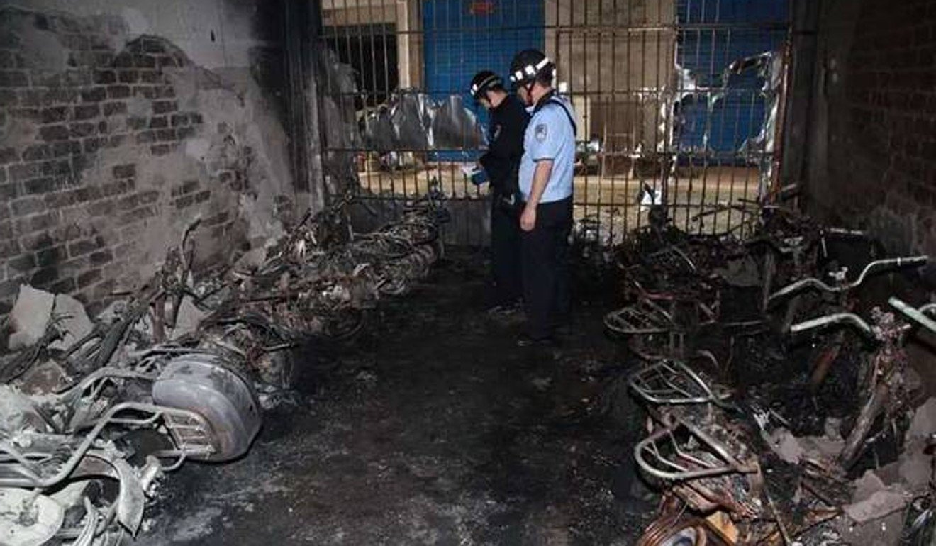 Fire and rescue officials inspect the burned wrecks of scooters at the dormitory building. Photo: Weibo