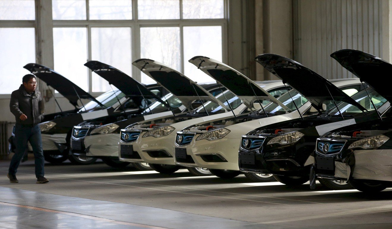 A man walks past cars at an assembly line producing electronic cars at a factory of Beijing Electric Vehicle in Beijing, China in 2016. Photo: Reuters