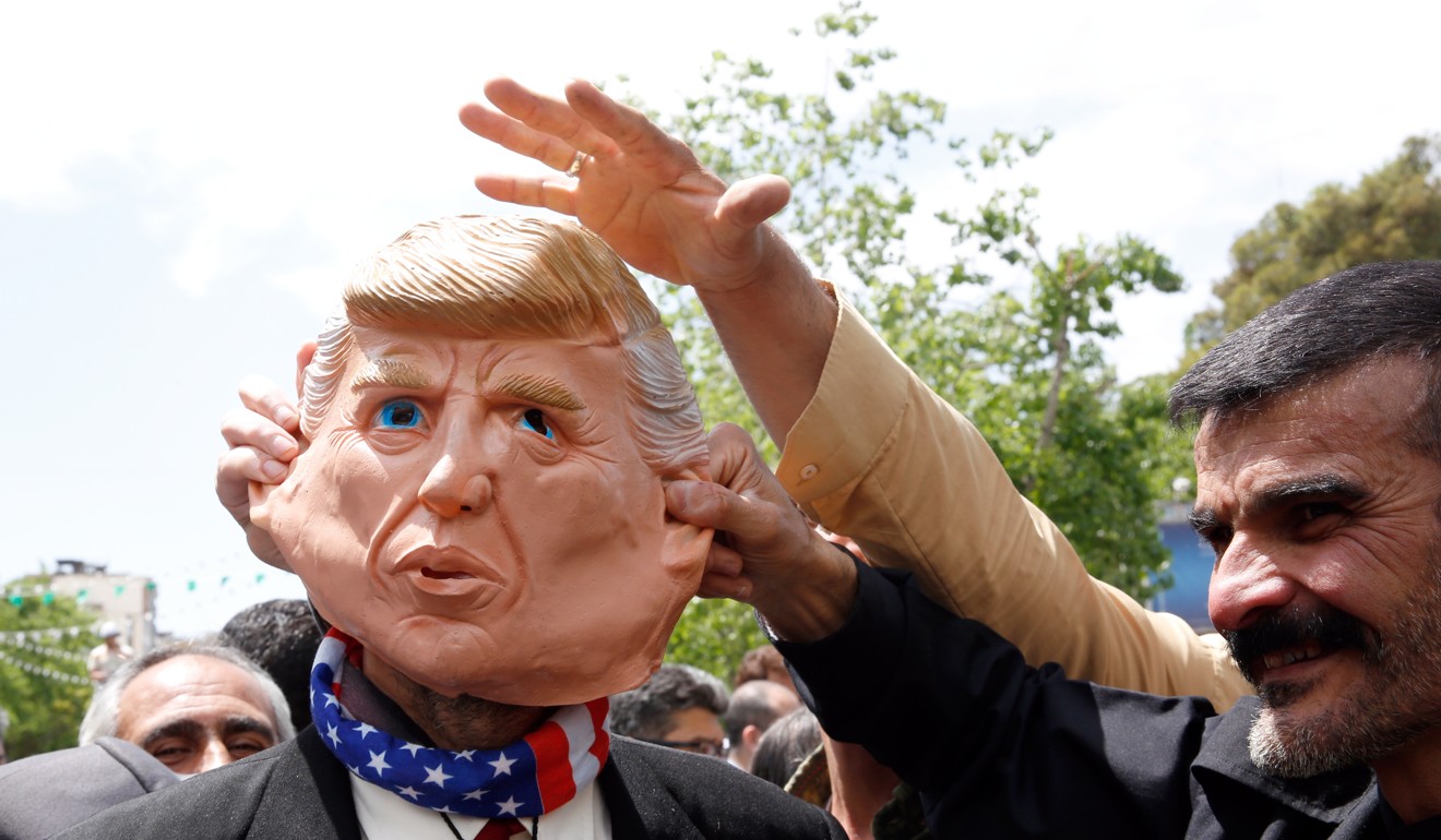 Demonstrators stand around an Iranian man that wears a mask of the US President Donald J. Trump during an anti-US rally. Photo: EPA-EFE