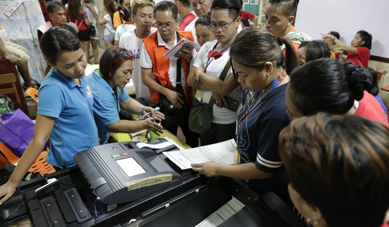 Election workers at a polling centre in Manila feed ballots into a vote counting machine after it was replaced due to a malfunction during the country's midterm elections. Photo: AP