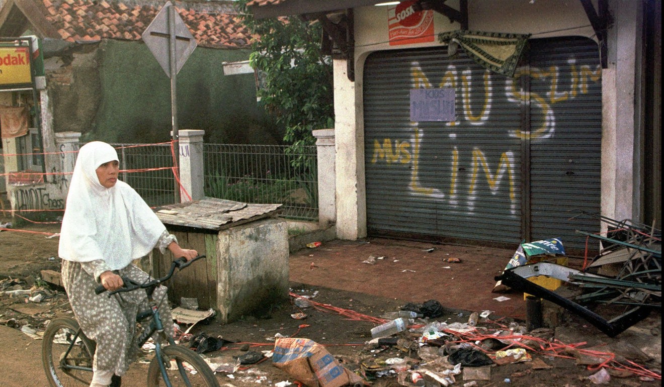 A woman cycles past a shopfront daubed with the words ‘Muslim’ by fearful non-Chinese residents to keep rioters from attacking their homes in Sukamandi in 1998. Photo: AP
