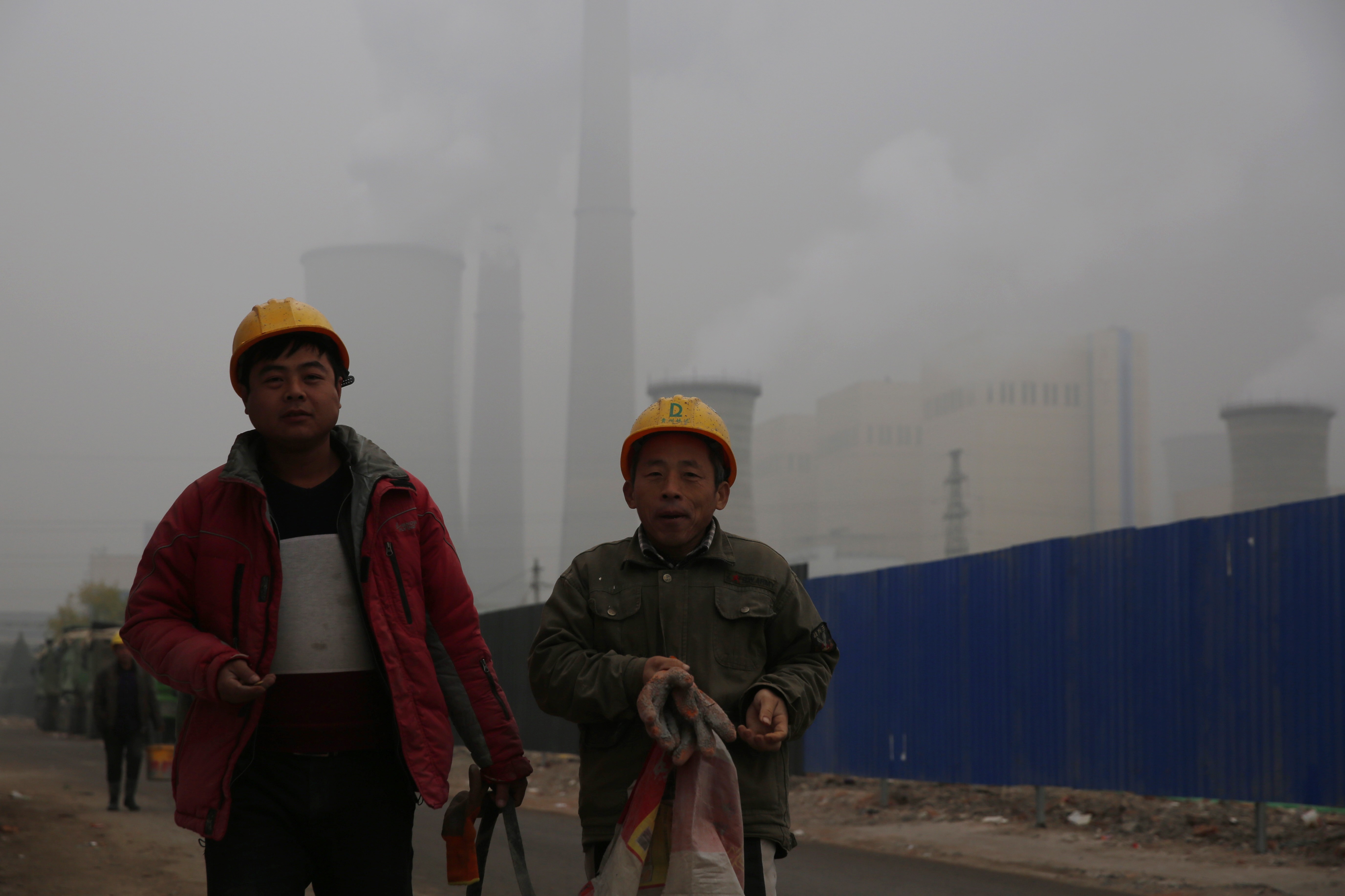 Workers walk near a power plant in Beijing during an especially polluted day in December 2018. China is the top emitter of carbon gases, but has had some success in capping emissions, particularly since 2013. Photo: EPA-EFE