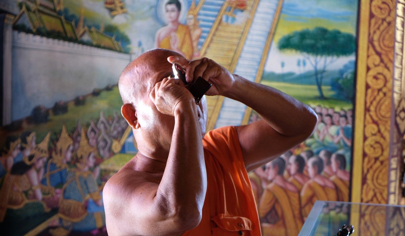 A Buddhist monk inspects an amulet at a temple in Bangkok. Palming off worthless fakes on unsuspecting customers has become a common scam at some Buddhist temples. Photo: Tibor Krausz