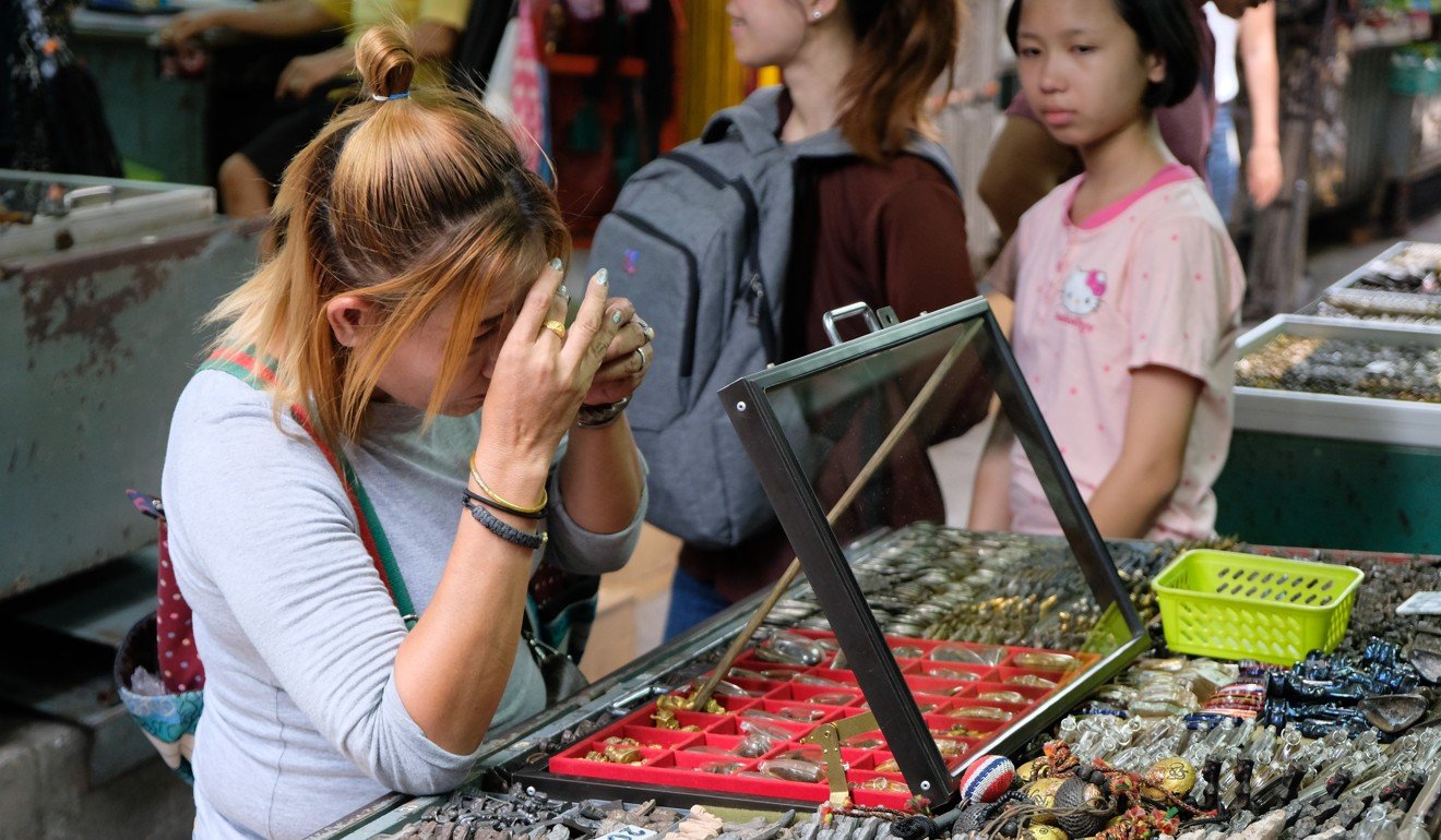 A woman examines an amulet for sale. Seven in 10 Thais wear amulets – some wear dozens at a time. Photo: Tibor Krausz