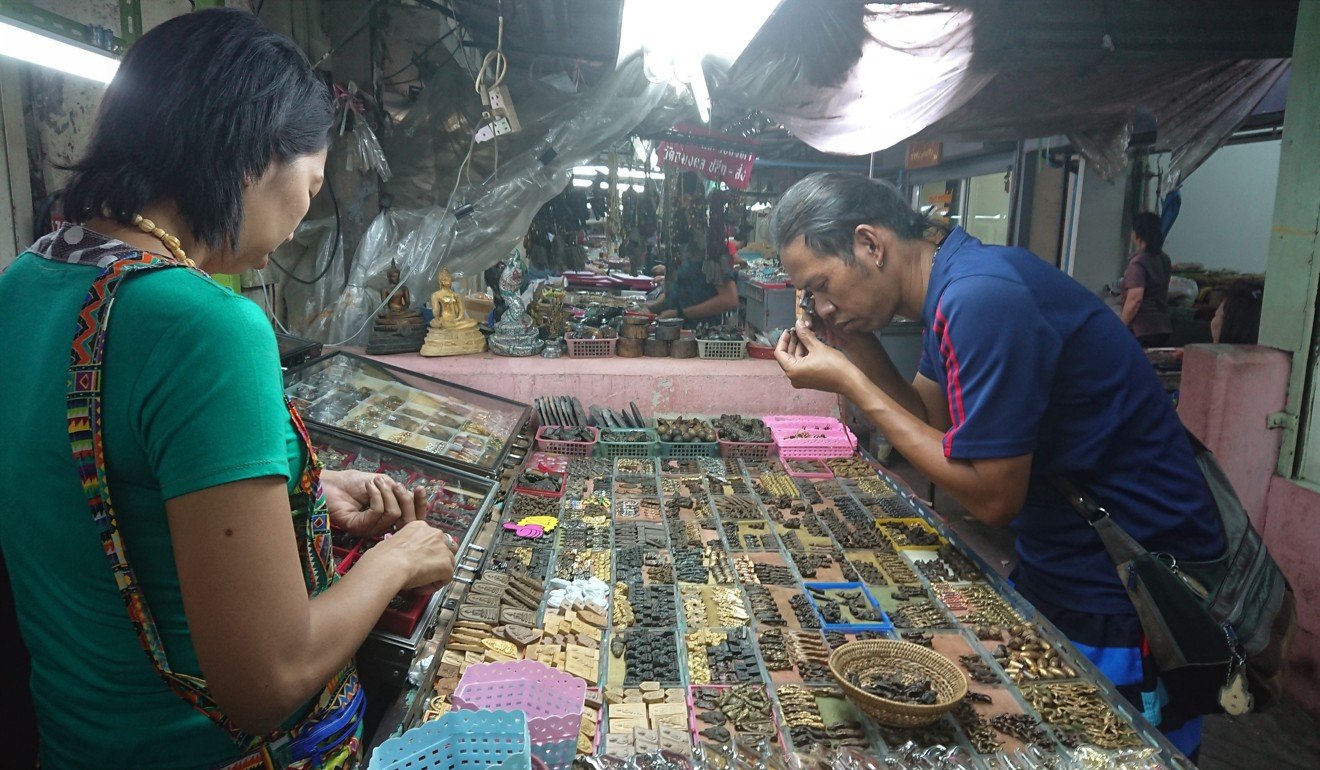 A customer inspects an amulet for sale at a Bangkok market. Even a mass-produced amulet demands close inspection before a purchase is made. Photo: Tibor Krausz