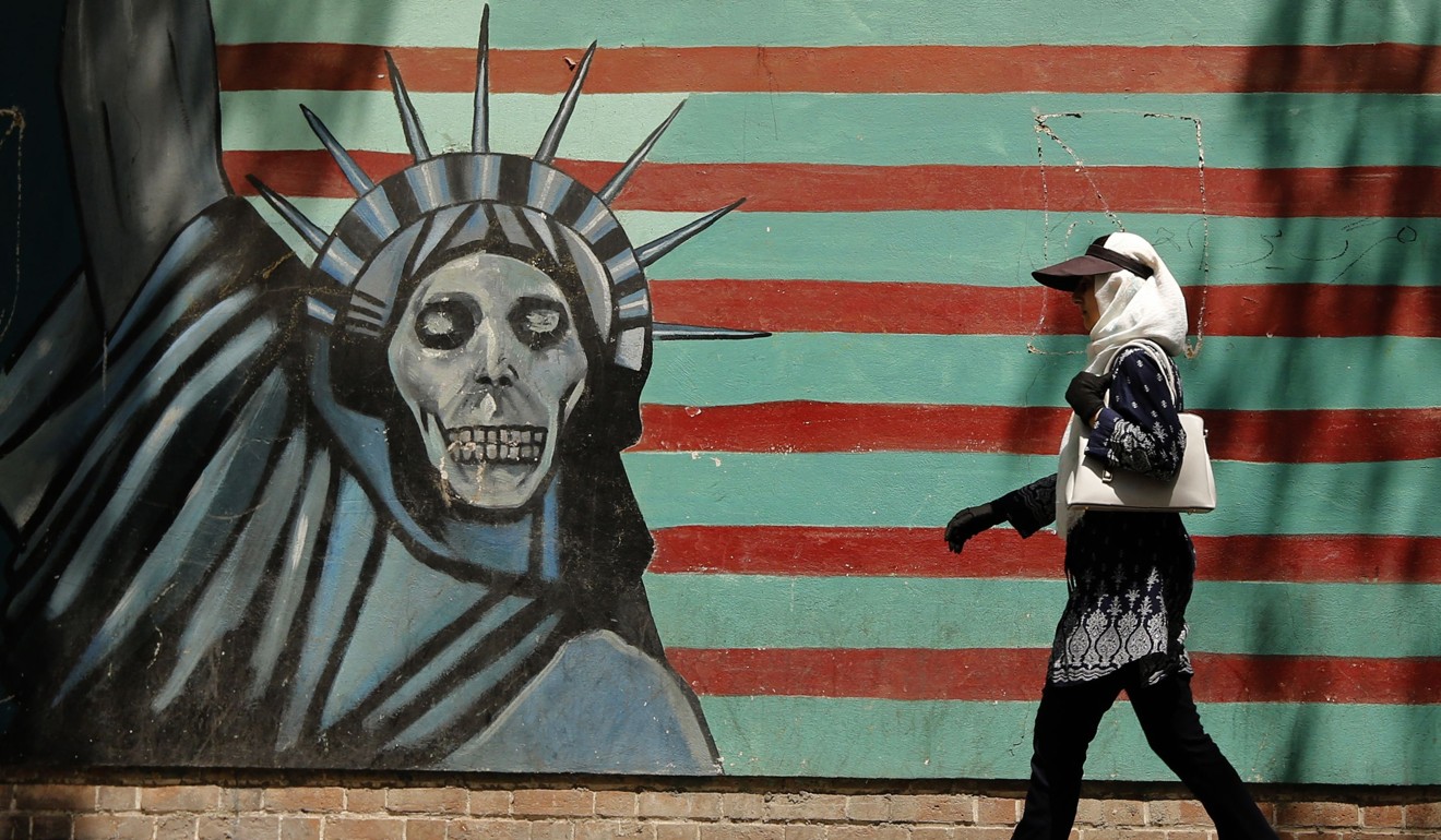 An Iranian woman walks past a mural on the wall of the former US embassy in Tehran on August 7, 2018. Photo: AFP