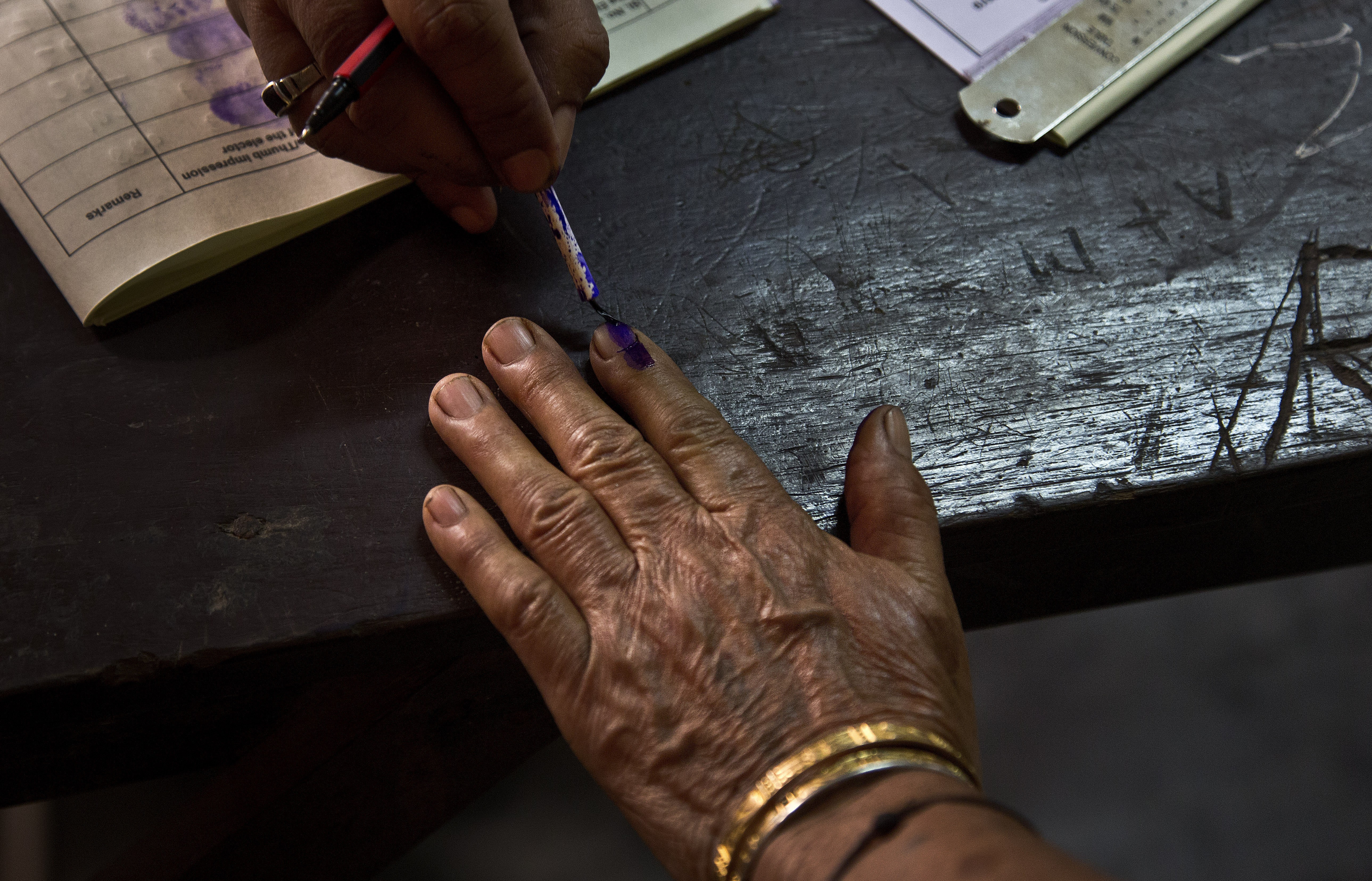 A polling officer puts an indelible ink mark on the index finger of an elderly voter at a polling station in Gauhati, India. Photo: AP