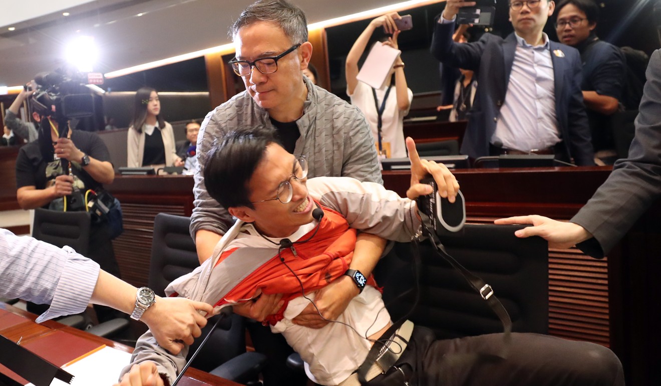 Legislator Paul Tse (centre top) holds back an agitated Eddie Chu. Photo: Winson Wong
